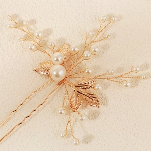 Détail d'une épingle à cheveux de mariée avec perles blanches et feuilles dorées