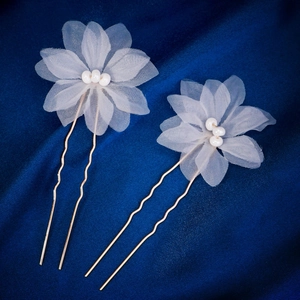 Détail d'épingles à cheveux fleurs en tulle blanc avec perles sur soie bleue