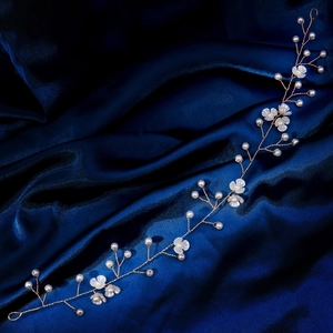 Détail d'un bandeau de mariée avec fleurs blanches et perles sur satin bleu nuit