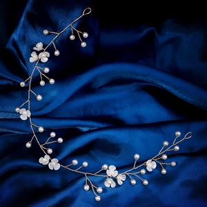 Détail d'un bandeau de mariée fait main avec fleurs blanches et perles sur fil doré