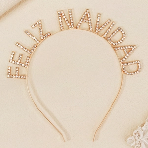 Close-up of golden headband featuring sparkly rhinestones spelling Feliz Navidad for parties