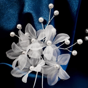 Détail de l'épingle à cheveux de mariée avec fleurs en résille blanches et perles sur soie