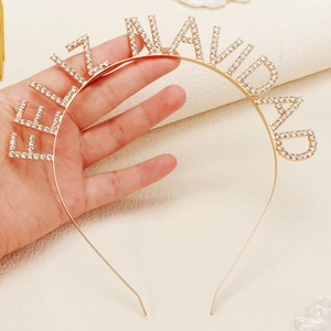 Close-up of golden Feliz Navidad headband featuring sparkling white rhinestones and lettering