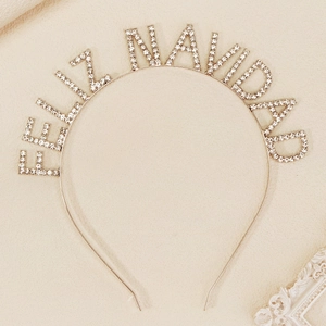 Detail of Feliz Navidad headband with sparkling rhinestones on elegant beige background