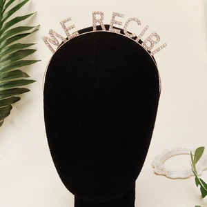 Macro shot of gold headband with ME RECIBI rhinestone lettering for graduation parties
