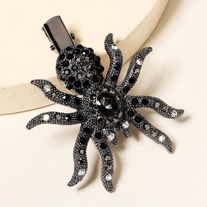Gothic spider hair clip with black and clear rhinestones on a warm beige background