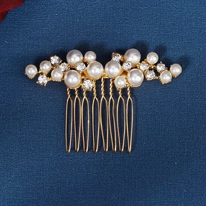 Close-up of elegant gold bridal hair comb with pearls and sparkling rhinestones