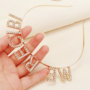 Detailed close-up of golden bridesmaid headband with sparkling rhinestone lettering