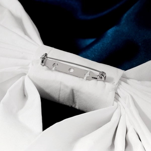 Detailed back view of white satin bow featuring a secure silver metal safety pin fastener