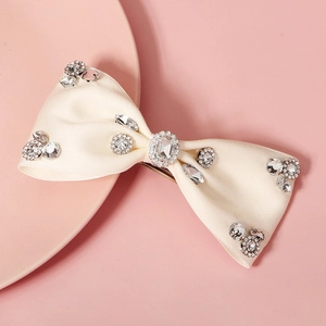 Elegant cream satin bow hair clip with sparkling rhinestones and a metal spring fastener