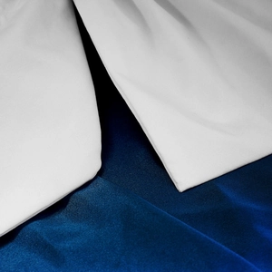 Detailed macro view of white plain weave and navy satin fabric layers with precise stitching