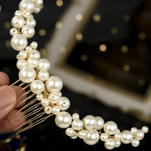 Detail of handmade bridal hair comb with pearls and gold wire on dark background
