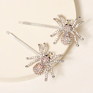 Close-up of sparkling rhinestone spider hair clips with silver metal finish on beige surface