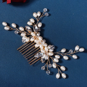 Close-up of gold bridal hair comb with elegant pearls and sparkling rhinestones