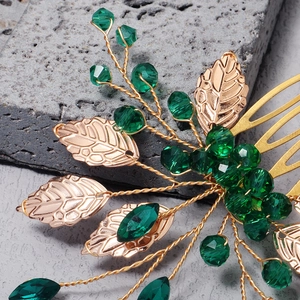 Macro shot of gold leaf bridal hair comb with green crystal beads on stone background