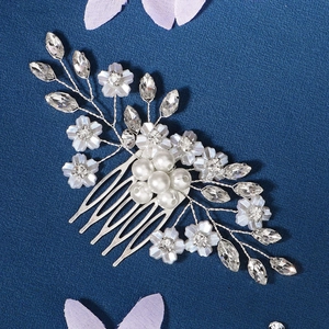Detail of handcrafted bridal hair comb with pearls and rhinestones on blue texture
