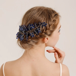 Détail d'un peigne à cheveux élégant avec cristaux bleu marine dans un chignon mariée