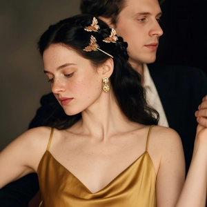 Detail of vintage gold 3D butterfly hair clips and earrings on a model in a romantic setting