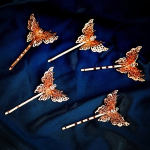 Detailed view of five golden filigree butterfly hair clips with sparkling rhinestones