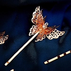 Detail of golden hollow butterfly hair clip with crystal on navy silk background