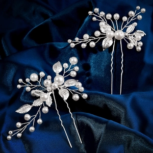 Détail de deux épingles à cheveux argentées avec perles et feuilles métalliques fines