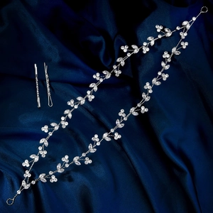 Detailansicht von silbernem Zirkon-Haarband und Haarnadeln auf blauem Seidenhintergrund