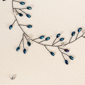 Détail d'un peigne de mariée fait main avec strass bleu roi et branches de fils noirs torsadés