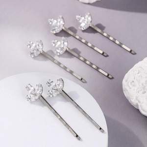 Détail macro de barrettes argentées avec zircons en trèfle sur fond violet pastel