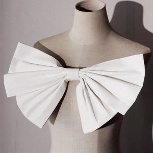 Detalle de un lazo grande de tela blanca con pliegues estructurados para vestidos de novia