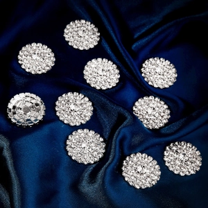 Macro view of round rhinestone flower buttons with silver base on blue silk fabric