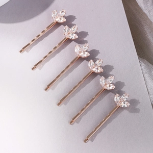 Lot de six barrettes dorées en forme de trèfle avec cristaux zircon sur fond gris épuré