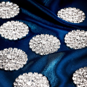 Macro shot of sparkling crystal rhinestone flower buttons on elegant navy blue satin fabric