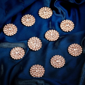 Detailed macro view of 10-piece rose gold rhinestone flower buttons on blue silk fabric