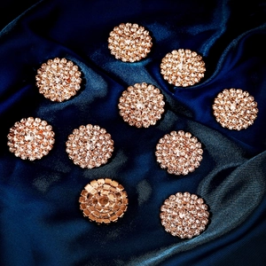 Detailed close-up of crystal flower buttons with gold metal base on blue silk fabric