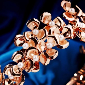 Detail of gold metal flower headband with white pearls on dark blue satin background