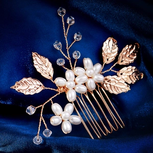 Macro detail of handmade bridal hair comb with golden leaves and white pearls