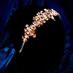 Detail of rose gold flower headband with pearls on black mannequin head with silk background