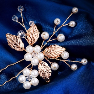 Detailed close-up of handmade gold leaf hair pins with pearls and crystals on blue silk