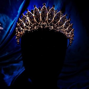 Detail of golden Baroque crown featuring deep black crystals and Gothic pattern design