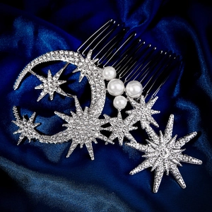 Detailed macro view of silver moon star hair comb with rhinestones and pearls on blue silk