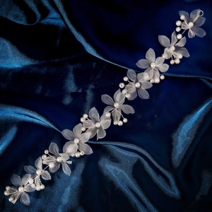 Détails de fleurs en tissu blanc et perles sur une vigne à cheveux de mariée en satin bleu
