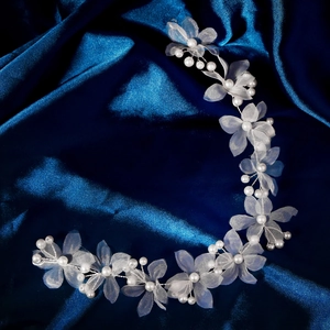 Détail de fleurs en organza blanc et perles sur un accessoire de coiffure de mariage