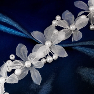 Détail d'un bandeau fleurs en organza fait main avec perles sur satin bleu
