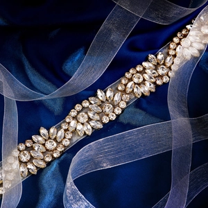 Détail macro d'une ceinture de mariée étincelante avec cristaux sur satin bleu foncé
