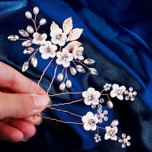 Détails d'un set d'épingles à cheveux de mariée avec fleurs blanches, perles et cristaux
