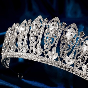 Detailed close-up of a silver bridal tiara with sparkling pear-cut rhinestones on blue silk