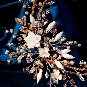 Macro shot of handmade bridal headpiece with white ceramic flowers and crystal pearls