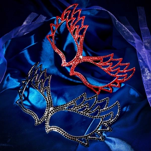 Detail of red and black winged rhinestone masquerade masks on elegant blue satin