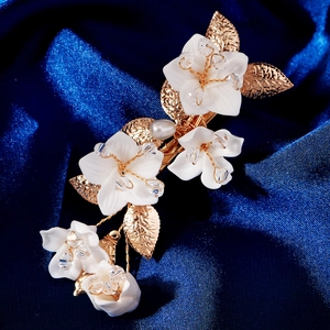 Dettaglio macro di un fermaglio per capelli con fiori in resina e foglie dorate