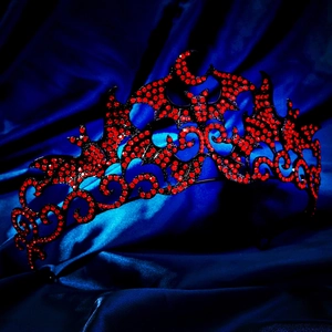 Gothic bat crown with red crystals for Halloween party on blue silk background